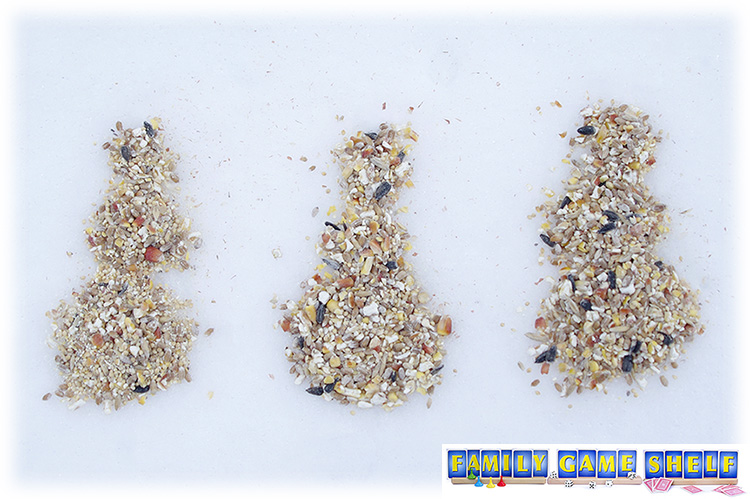 Three snowmen drawn in birdseed