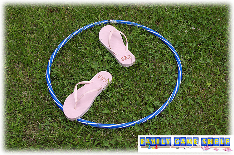 A hula hoop on the ground with flip flops in it