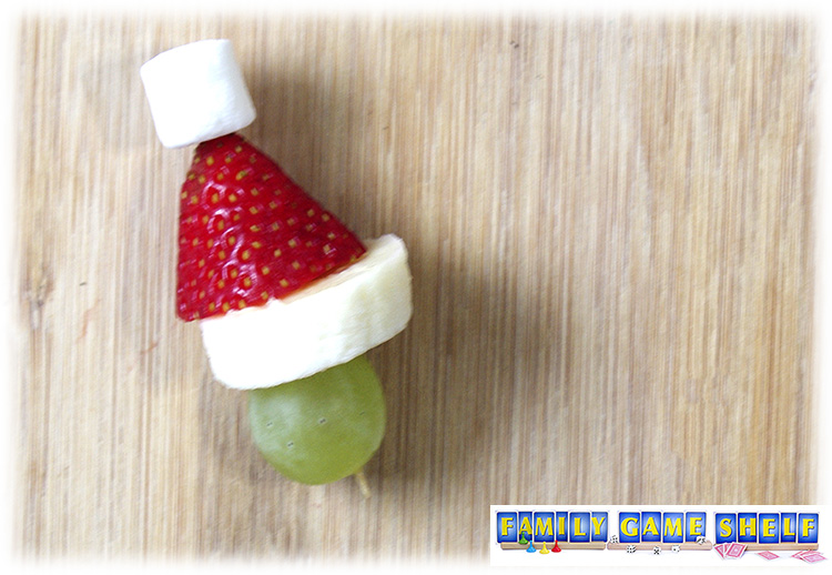 Grinch Party snack of a kabob with a green grape, banana slice, strawberry and a marshmallow