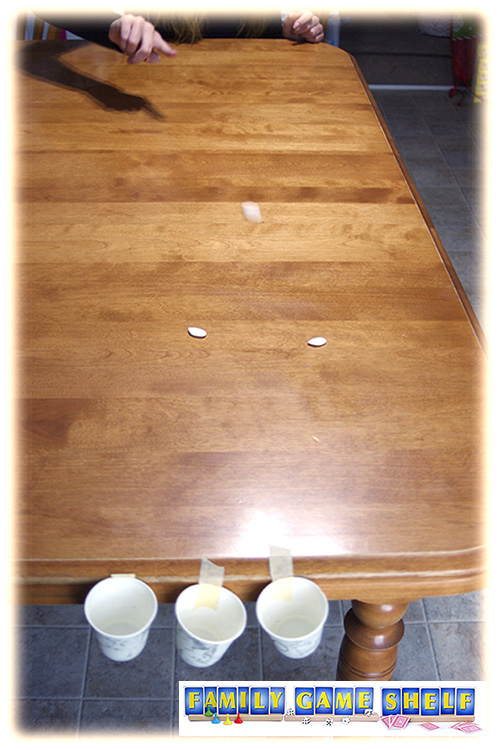 Pumpkin Seed Minute to Win it Games player sliding seeds across the table to the taped cups