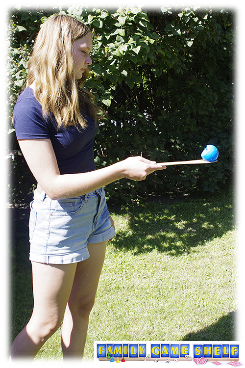 girl holding a water balloon on a wooden spoon