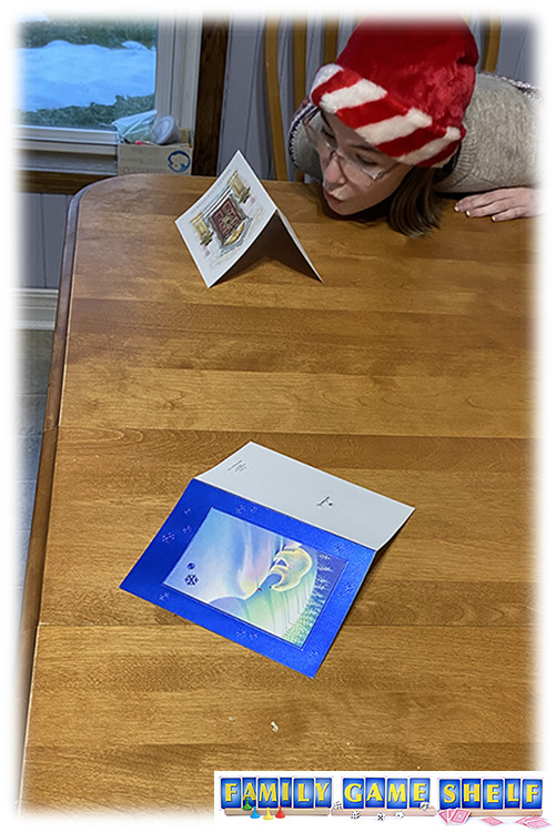 Don't Be Last Christmas player blowing a Christmas card on a table