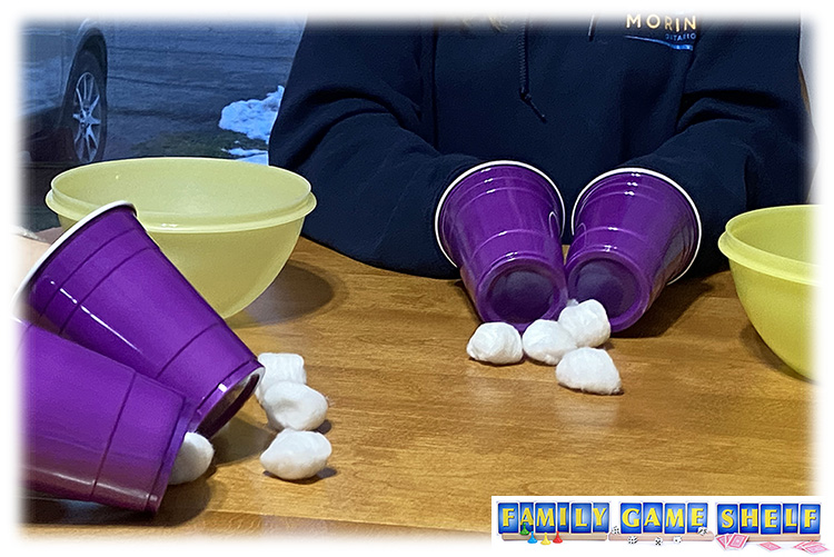 Players with plastic cups on their hands picking up cotton ballls