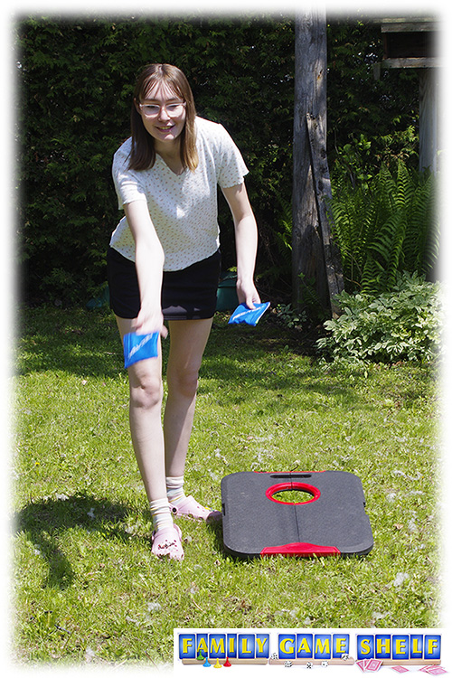 A woman throwing a beanbag