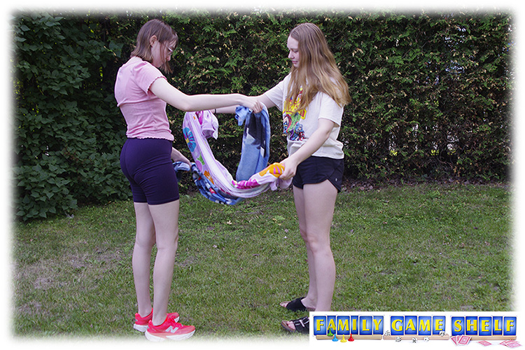 Two girls both holding towels that are connected