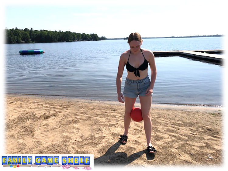 Best beach games knee ball race showing a girl with a ball between her knees on the beach