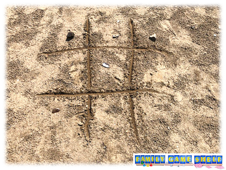 tic tac toe in the sand using shells and rocks
